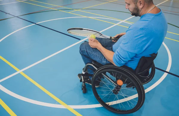 Erwachsener Mann mit körperlicher Behinderung, der Rollstuhl benutzt, um Tennis auf dem Tennisplatz zu spielen — Stockfoto