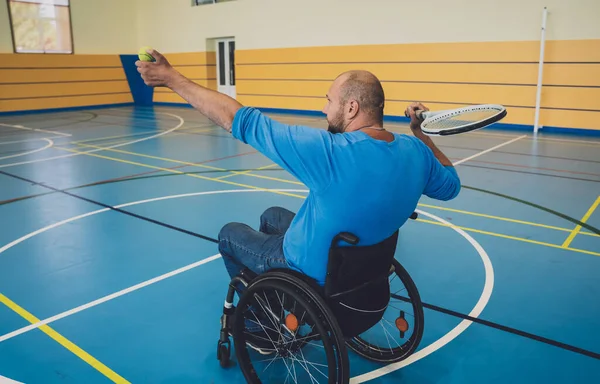 Hombre adulto con discapacidad física que utiliza silla de ruedas jugando al tenis en pista de tenis cubierta —  Fotos de Stock