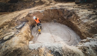 İşçi, bir güç aktarım istasyonunun yapımında taşınabilir titreşim rampası kullanıyor