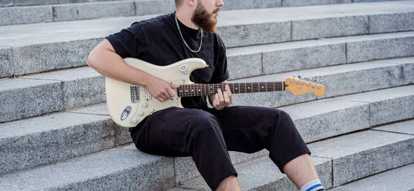 Gitar çalan genç sokak müzisyeni granit merdivenlerde oturuyor. — Stok fotoğraf