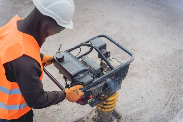 Arbetstagaren använder en portabel vibrationsstämpel vid konstruktionen av en kraftöverföringsstation — Stockfoto