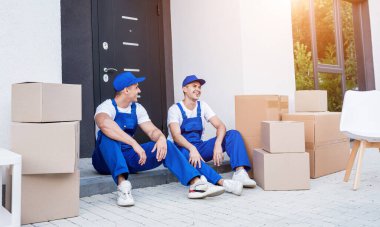 İki nakliye şirketi çalışanı merdivende otururken mola veriyor.