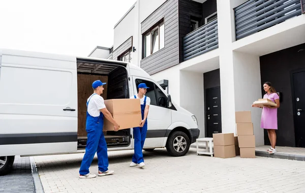 Two removal company workers unloading boxes from minibus into customers home — Stock Photo, Image