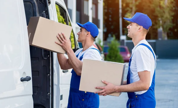 İki nakliye şirketi çalışanı bir minibüse kutu yüklüyorlar..