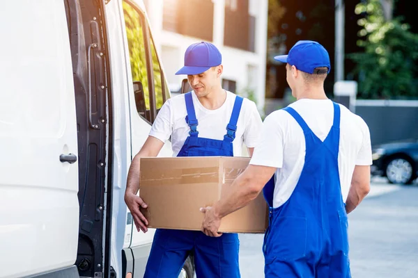 Two removal company workers are loading boxes into a minibus. — Stock Photo, Image