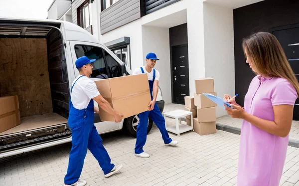 İki nakliye şirketi çalışanı minibüsten müşterilerin evlerine kutu indiriyor.