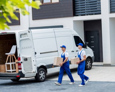 İki nakliye şirketi çalışanı bir minibüse kutu ve mobilya yüklüyorlar..