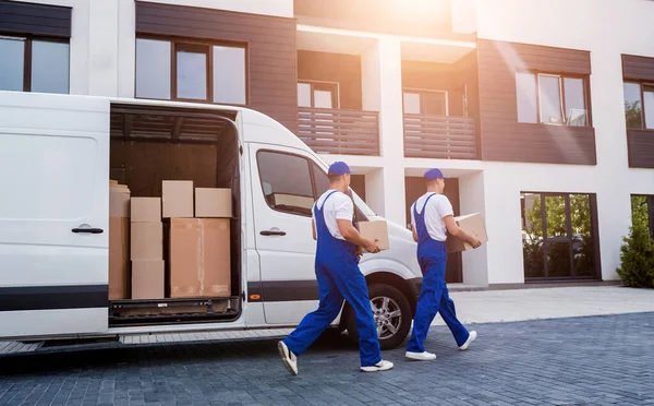 Two removal company workers unloading boxes from minibus into new home — Stock Photo, Image