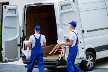 İki nakliye şirketi çalışanı bir minibüse kutu ve mobilya yüklüyorlar..