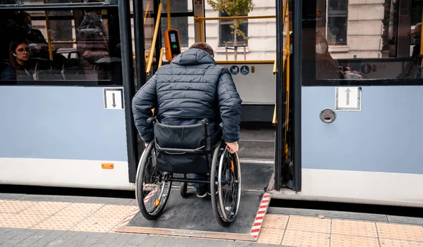 Osoba s tělesným postižením vstupuje do veřejné dopravy s přístupnou rampou. — Stock fotografie