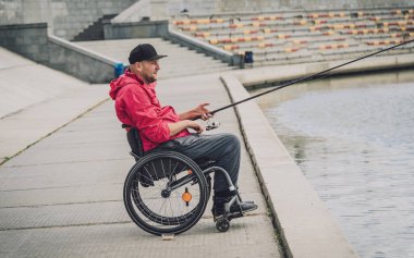 Balıkçı iskelesinden tekerlekli sandalyede balık tutan fiziksel engelli biri..