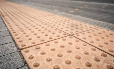 Fiziksel engelli kişiler için toplu taşıma istasyonunda sarı kabartma yazılar