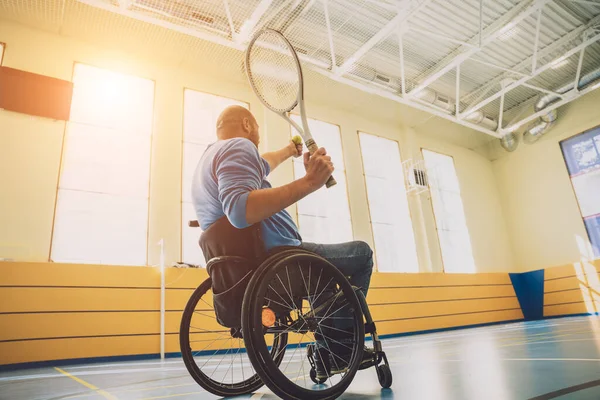 Hombre adulto con discapacidad física que utiliza silla de ruedas jugando al tenis en pista de tenis cubierta —  Fotos de Stock