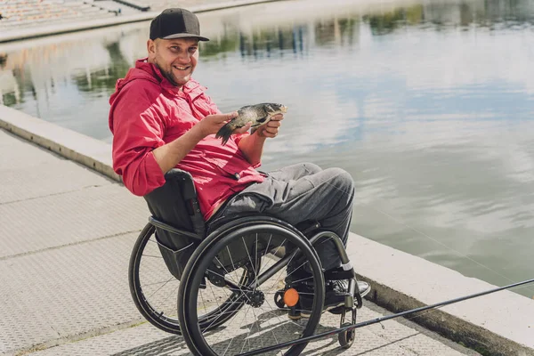 Persona con discapacidad física que utiliza la pesca en silla de ruedas desde el muelle de pesca. — Foto de Stock