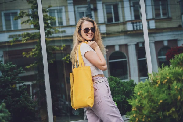 Jeune belle femme avec sac écologique en lin sur fond de ville. — Photo