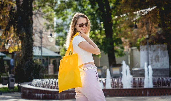 Jeune belle femme avec sac écologique en lin sur fond de ville. — Photo