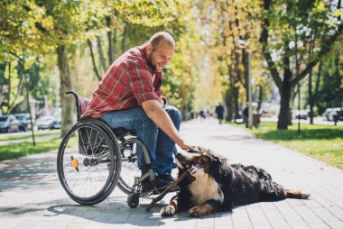 Köpeğiyle tekerlekli sandalye kullanan fiziksel engelli genç adam..