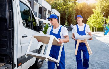 İki nakliye şirketi çalışanı bir minibüse kutu ve mobilya yüklüyorlar..