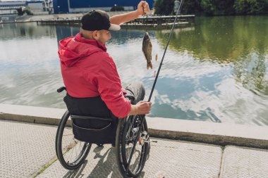 Balıkçı iskelesinden tekerlekli sandalyede balık tutan fiziksel engelli biri..