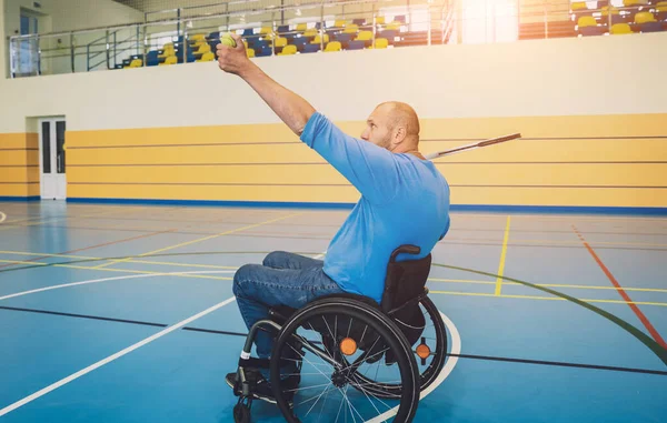 Erwachsener Mann mit körperlicher Behinderung, der Rollstuhl benutzt, um Tennis auf dem Tennisplatz zu spielen — Stockfoto