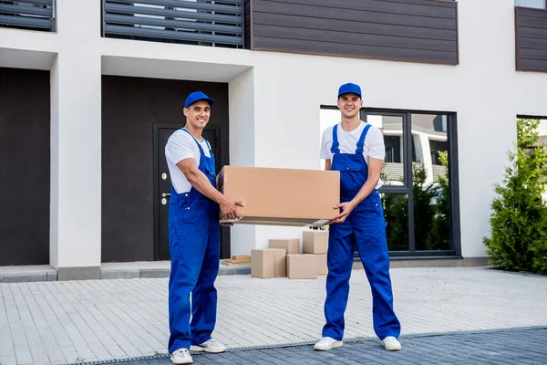 Zwei Mitarbeiter einer Umzugsfirma laden Kisten aus Kleinbus in neues Zuhause — Stockfoto