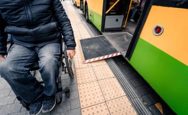 Fiziksel engelli kişiler toplu taşımadan erişilebilir bir rampayla çıkıyorlar..