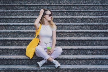 Genç ve güzel bir kadın. Arka planda keten bir çanta var..