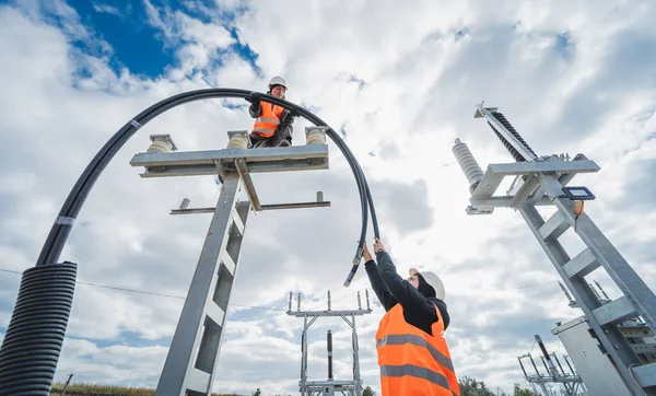 Dos trabajadores electricistas instalando cable de alta tensión — Foto de Stock