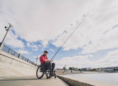 Balıkçı iskelesinden tekerlekli sandalyede balık tutan fiziksel engelli biri..