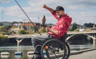 Balıkçı iskelesinden tekerlekli sandalyede balık tutan fiziksel engelli biri..