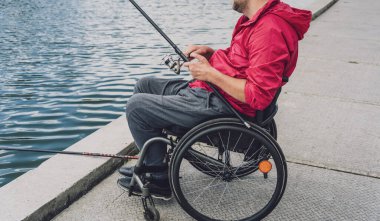 Balıkçı iskelesinden tekerlekli sandalyede balık tutan fiziksel engelli biri..