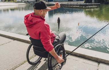 Balıkçı iskelesinden tekerlekli sandalyede balık tutan fiziksel engelli biri..