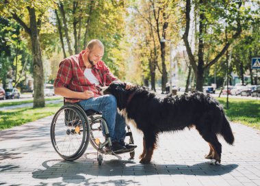 Köpeğiyle tekerlekli sandalye kullanan fiziksel engelli genç adam..