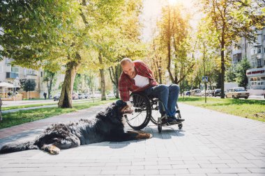 Köpeğiyle tekerlekli sandalye kullanan fiziksel engelli genç adam..