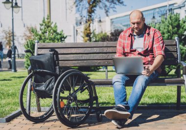 Parkta tekerlekli sandalye kullanan fiziksel engelli bir serbest çalışan.