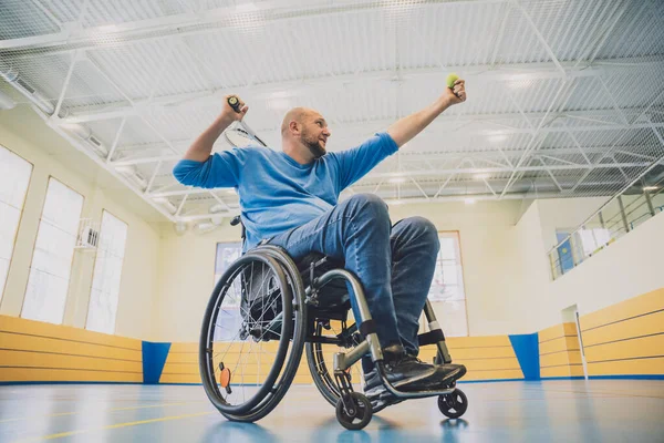 Erwachsener Mann mit körperlicher Behinderung, der Rollstuhl benutzt, um Tennis auf dem Tennisplatz zu spielen — Stockfoto