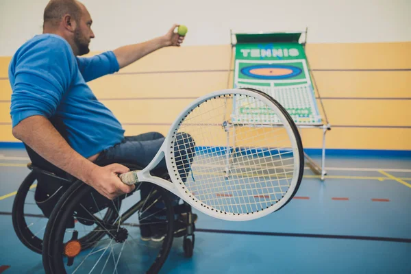 Hombre adulto con discapacidad física que utiliza silla de ruedas jugando al tenis en pista de tenis cubierta — Foto de Stock