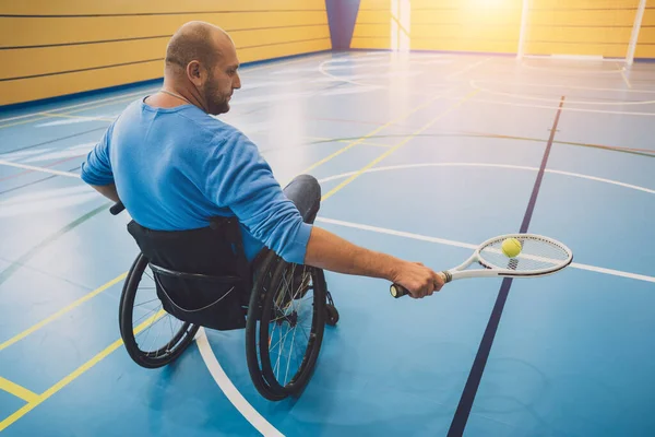 Erwachsener Mann mit körperlicher Behinderung, der Rollstuhl benutzt, um Tennis auf dem Tennisplatz zu spielen — Stockfoto