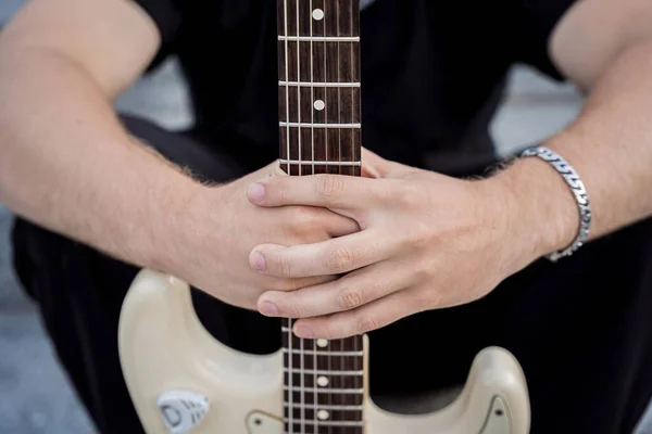 Jonge straatmuzikant die gitaar speelt zittend op granieten treden — Stockfoto