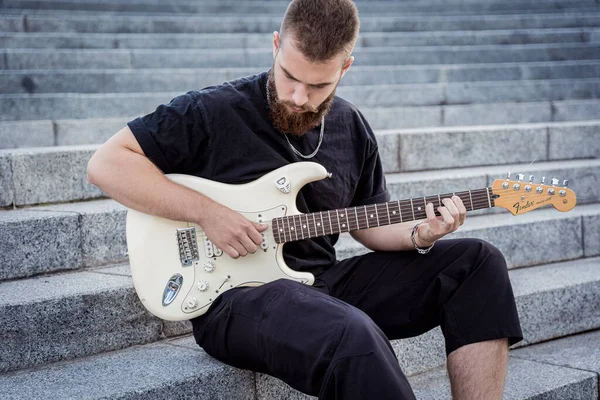 Gitar çalan genç sokak müzisyeni granit merdivenlerde oturuyor. — Stok fotoğraf