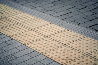 Fiziksel engelli kişiler için toplu taşıma istasyonunda sarı kabartma yazılar