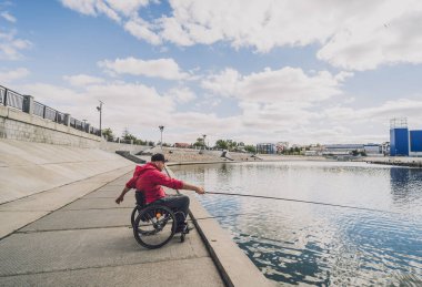 Balıkçı iskelesinden tekerlekli sandalyede balık tutan fiziksel engelli biri..