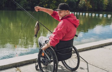 Balıkçı iskelesinden tekerlekli sandalyede balık tutan fiziksel engelli biri..