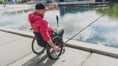 Balıkçı iskelesinden tekerlekli sandalyede balık tutan fiziksel engelli biri..