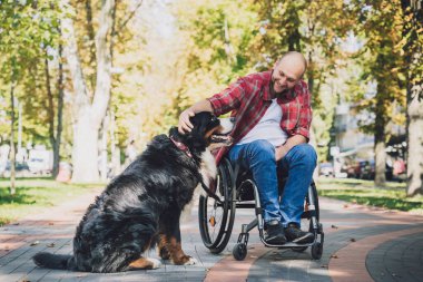 Köpeğiyle tekerlekli sandalye kullanan fiziksel engelli genç adam..