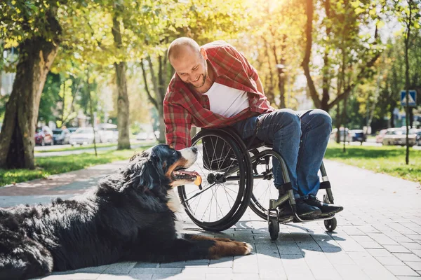 Happy young man with a physical disability who uses wheelchair with his dog. — Stock Photo, Image