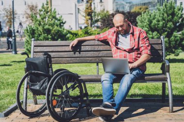 Parkta tekerlekli sandalye kullanan fiziksel engelli bir serbest çalışan.