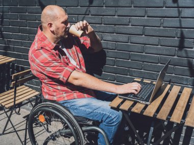 Sokak kafesinde çalışan ve tekerlekli sandalye kullanan fiziksel engelli bir serbest çalışan.