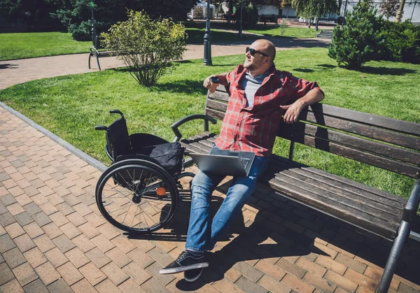 Freelancer con discapacidad física que utiliza silla de ruedas trabajando en el parque —  Fotos de Stock