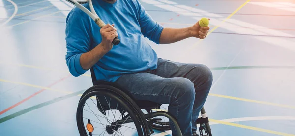 Adult man with a physical disability who uses wheelchair playing tennis on indoor tennis court — Stock Photo, Image